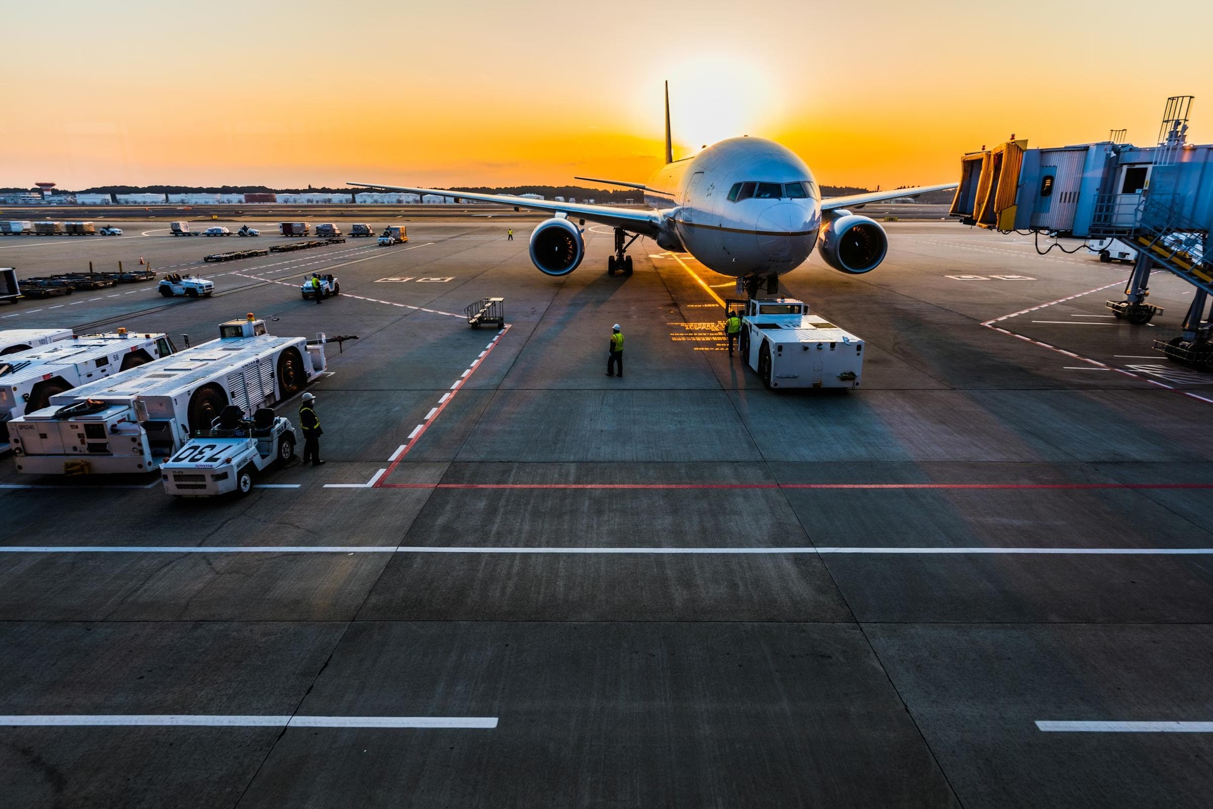 An aircraft on stand at dusk, jet bridge connected.